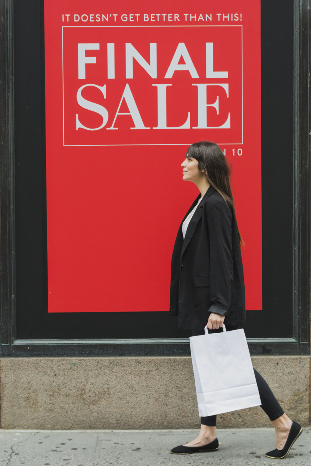 Woman walking past Sale sign